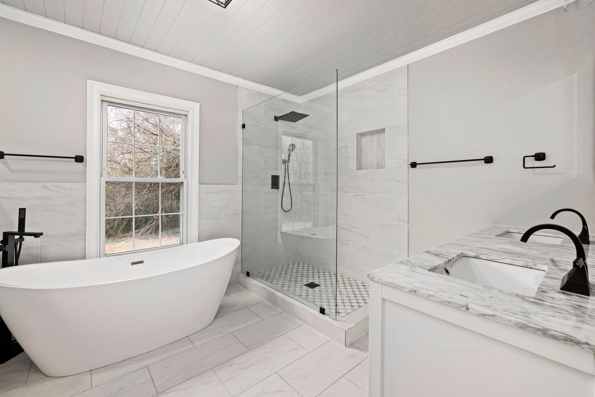 Sleek bathroom featuring a freestanding tub, glass shower, and marble accents.